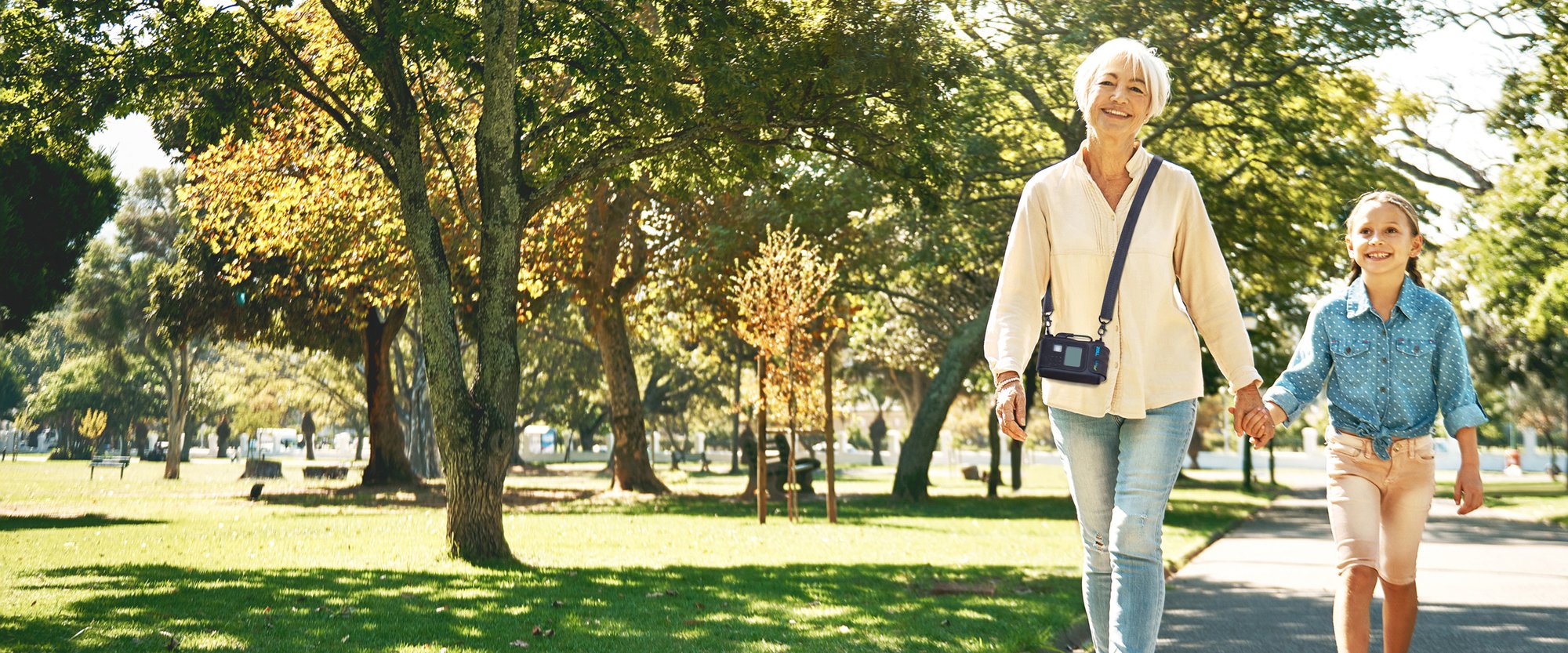 A woman wearing a ZOLL LifeVest walking outdoors with her granddaughter