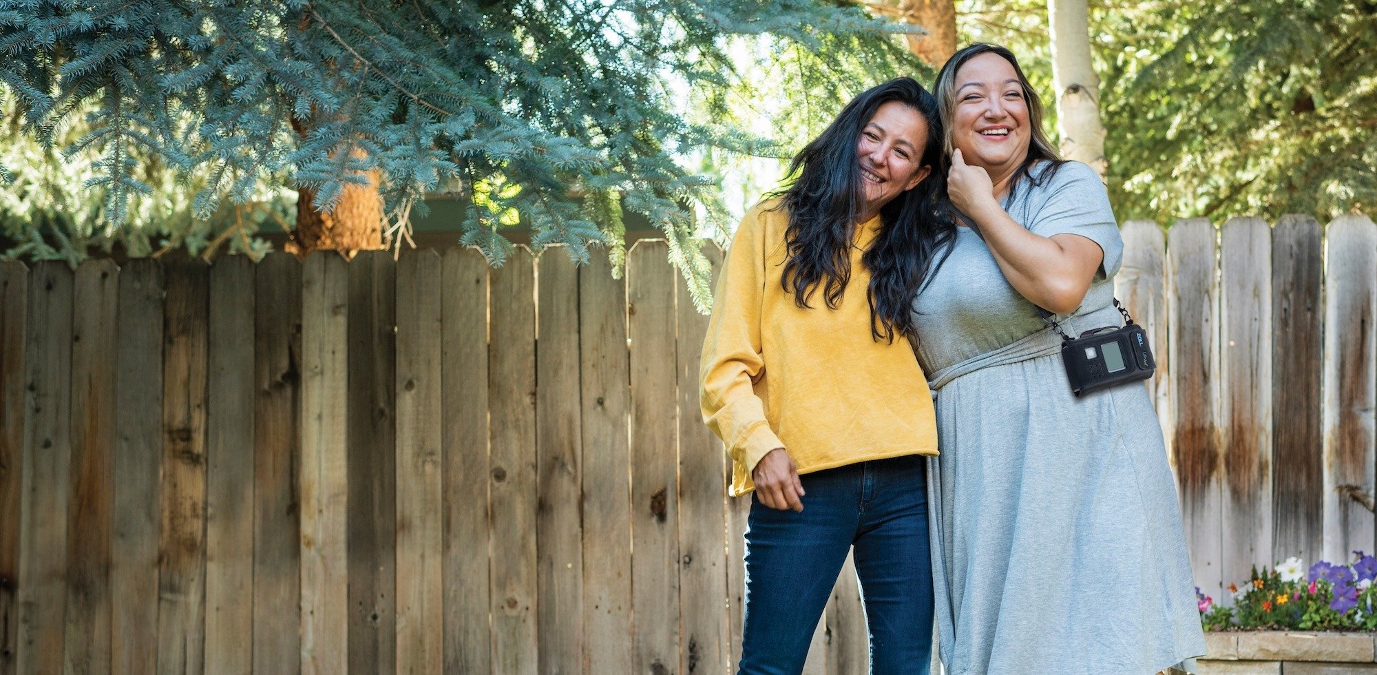 A woman wearing a ZOLL LifeVest smiles outdoors with a friend.