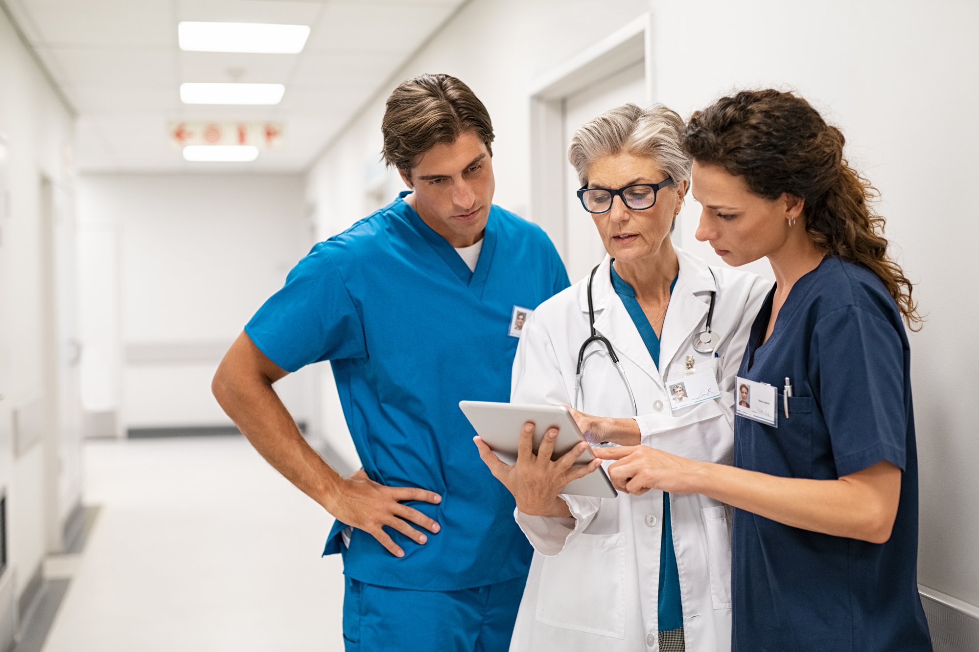 Medical professionals looking at a tablet in hospital hallway